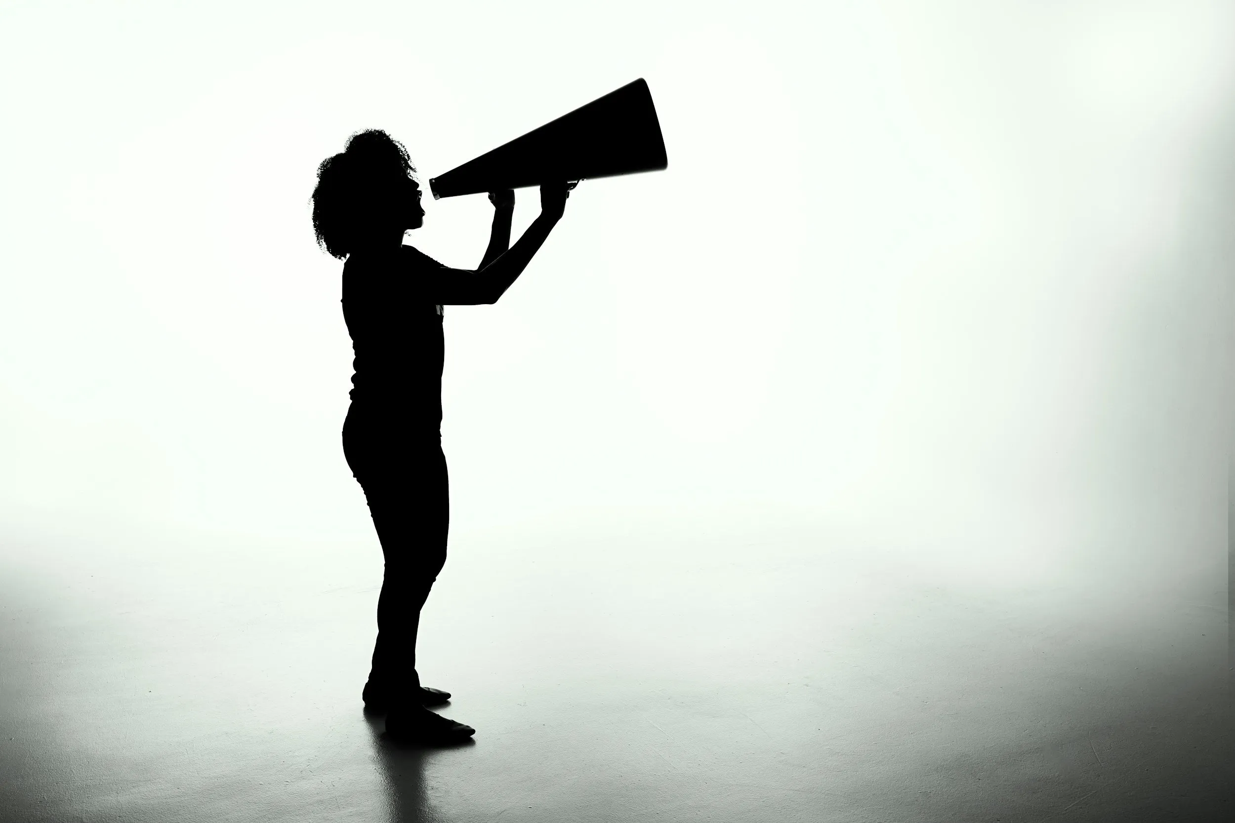 A person speaking loudly through a megaphone, illustrating Parkinson's voice therapy